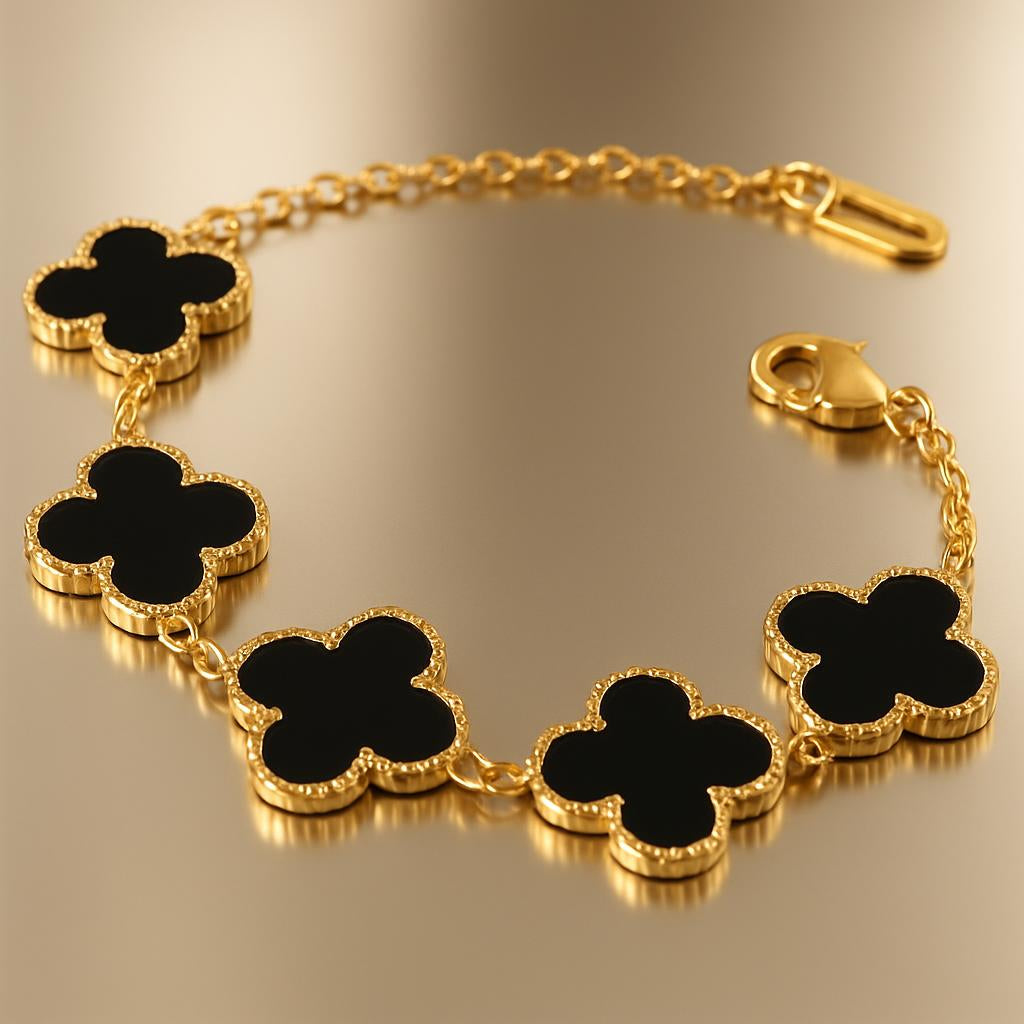 A close-up shot of the luxury 18K gold-plated black clover bracelet laid on a sleek, reflective surface, highlighting the intricate gold edges and the black steel inlay of the charms, with soft, diffused lighting emphasizing the brilliance and anti-tarnish