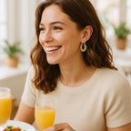 Lifestyle scene of a woman wearing the gold scallop hoop earrings during a brunch with friends, capturing a natural smile and the playful, elegant vibe of the earrings in a bright, airy setting.