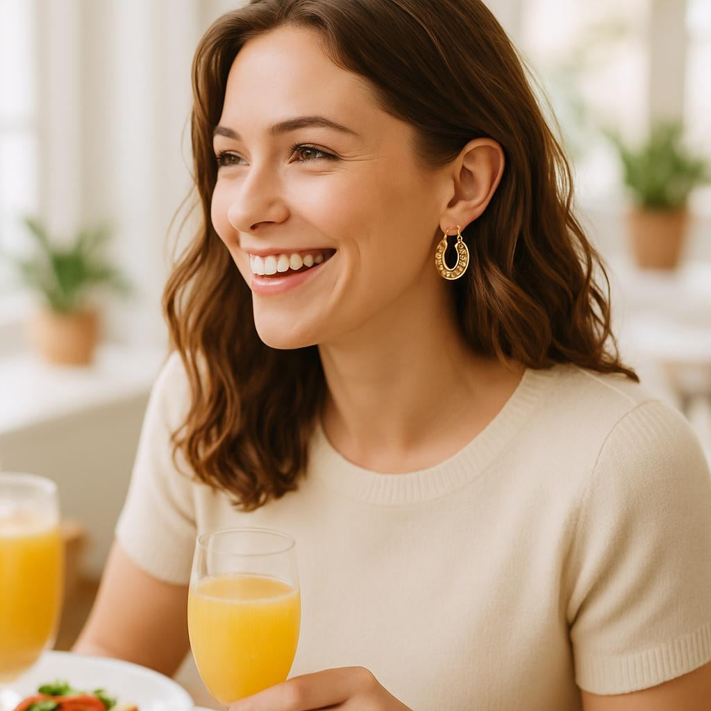 Lifestyle scene of a woman wearing the gold scallop hoop earrings during a brunch with friends, capturing a natural smile and the playful, elegant vibe of the earrings in a bright, airy setting.