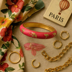 An artistic flat lay composition of the bangle alongside accessories like a floral scarf, gold jewelry, and a travel-themed item, arranged on a textured fabric background to evoke a sense of adventure, femininity, and style.