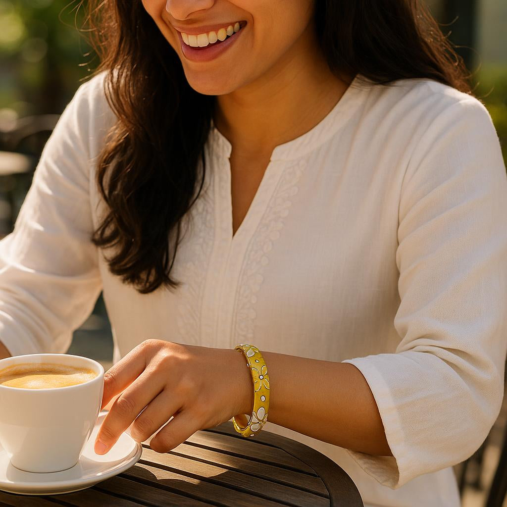 A lifestyle scene of a woman wearing the bangle with a white kurta, sitting outdoors at a sunny café table, capturing the joyful moment as she reaches for her coffee, with sunlight reflecting off the crystals.